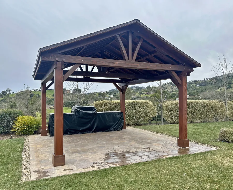 Custom Del Norte Outdoor Kitchen Pavilion (Options: 16' L x 16' W, Douglas-fir, No Privacy Panel, Post Anchor Kit for High Wind, 9.5' H Posts, No Ceiling Fan Base, 4 Electrical Wiring Trims, No Curtain Rod, Coffee Stain Premium Sealant). The color of the Coffee stain is lighter on the posts because they were refinished while the rest of the structure's finish is over a year old. Photo Courtesy of P. Boeck of Santa Rosa, CA.