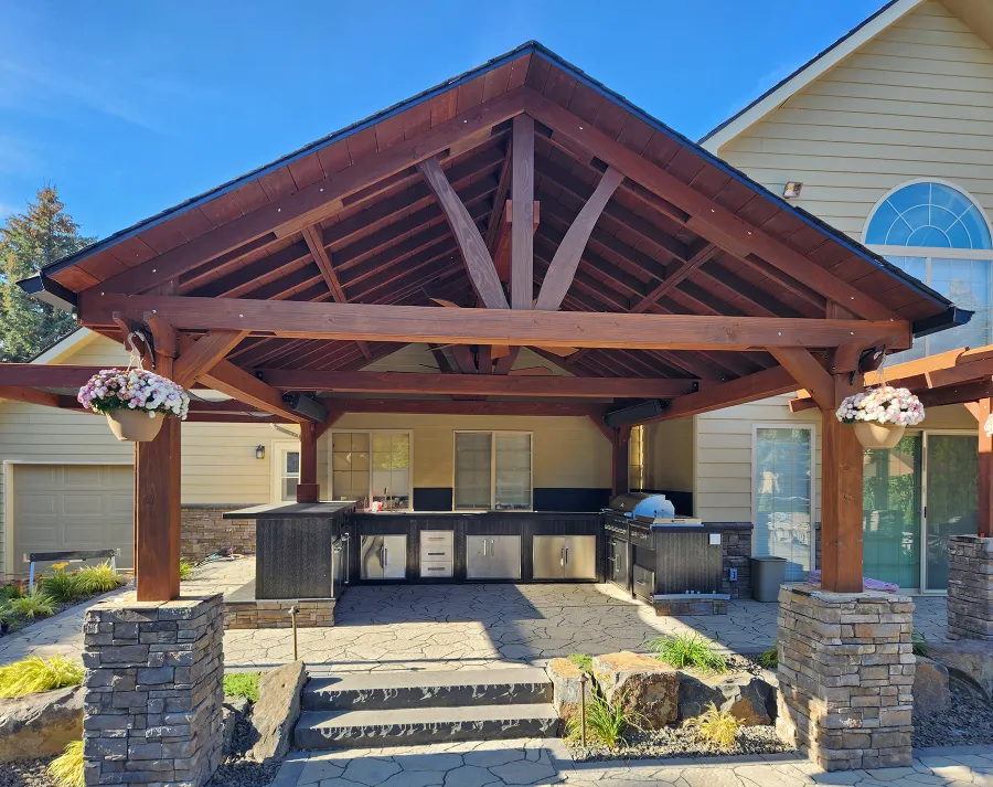 Del Norte Outdoor Kitchen Pavilion (Options: 19.5' L x 17' W, Mature Redwood, No Privacy Panel, Post Anchor Kit for High Wind, 10.5' H Posts, 1 Ceiling Fan Base, Electrical Wiring Trim for 2 Posts, No Curtain Rod, Coffee-Stain Premium Sealant). Photo Courtesy of Elements Landscaping of Hayden, ID.