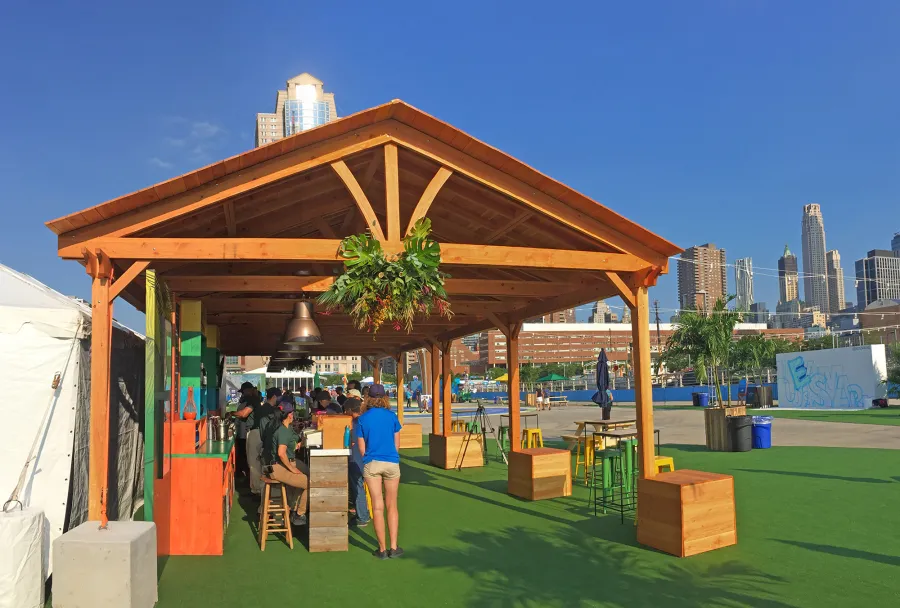 Rio on the Hudson: Olympic Village in NYC. 2 Del Norte Outdoor Kitchen Pavilions (Options: 25' L x 20' W, Douglas-fir, We used 2' x 2' x 2'  Concrete Blocks to Anchor the Structure Because it is a Temporary Installation, Covered the Concrete Blocks with Wooden Boxes, No Ceiling Fan Base, Transparent Premium Sealant). Photo Courtesy of A. Fisher of New York, NY.