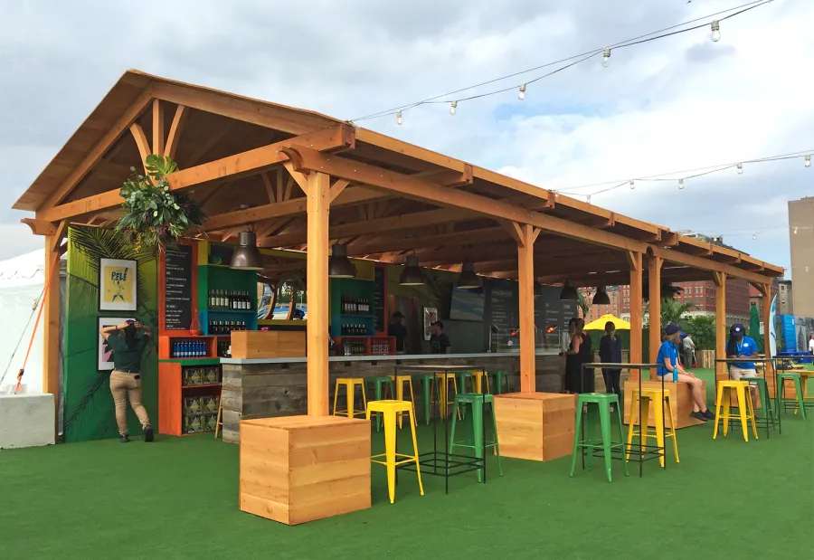 Rio on the Hudson: Olympic Village in NYC. 2 Del Norte Outdoor Kitchen Pavilions (Options: 25' L x 20' W, Douglas-fir, We used 2' x 2' x 2'  Concrete Blocks to Anchor the Structure Because it is a Temporary Installation, Covered the Concrete Blocks with Wooden Boxes, No Ceiling Fan Base, Transparent Premium Sealant). Photo Courtesy of A. Fisher of New York, NY.