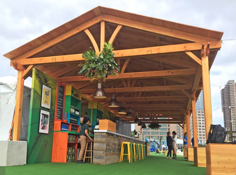 Rio on the Hudson: Olympic Village in NYC. 2 Del Norte Outdoor Kitchen Pavilions (Options: 25' L x 20' W, Douglas-fir, We used 2' x 2' x 2'  Concrete Blocks to Anchor the Structure Because it is a Temporary Installation, Covered the Concrete Blocks with Wooden Boxes, No Ceiling Fan Base, Transparent Premium Sealant). Photo Courtesy of A. Fisher of New York, NY.