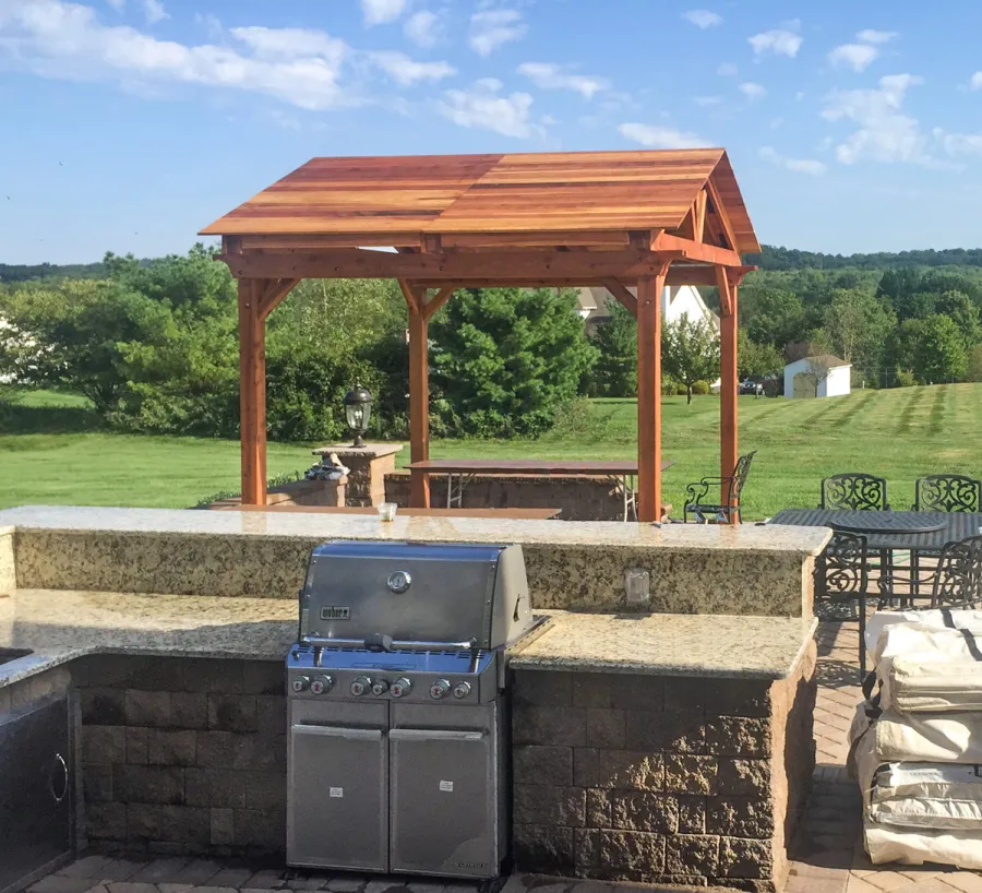 Del Norte Outdoor Kitchen Pavilion (Options: 12' L x 12' W, California Redwood, Unattached, 4-Post Anchor Kit for Concrete, Electrical Wiring Trim for 1 Post, 9' Posts, No Ceiling Fan Base, No Privacy Panels, No Curtain Rods, Transparent Premium Sealant). Photo Courtesy of Manjit Guleria of Pennington, NJ.