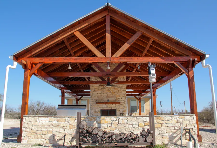 Del Rio Cathedral Ceiling Thick Timber Pavilion (Options: 42' L x 22' Triangle Base W, No Privacy Panels, Mature Redwood, 10' ft Height, Electrical Wiring Trim for 1 Post, 6-Post Anchor Kit for High-Wind, No Post Decorative Trim, 2 Ceiling Fan Bases, No Curtain Rods, Transparent Premium Sealant). Note: Fireplace and kitchen counter was added after the Pavilion was installed by a Mason.  Forever Redwood does not do masonry work, but our designs can incorporate them.