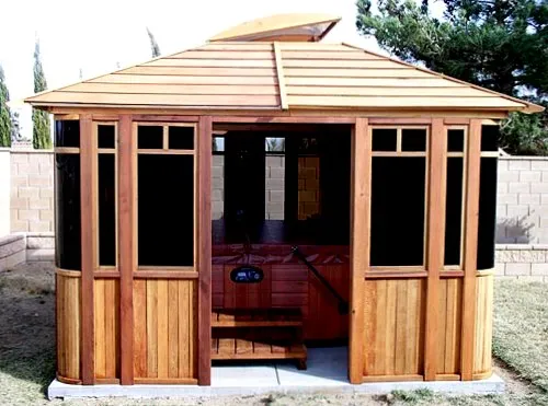DIY Wood Gazebo (14' L, 12' W, Mature Redwood, Sliding Windows, 4' x 6' Skylight, 24" H Siding Below Windows, Vertical Siding, Japanese Doors, No Flooring, Transparent Premium Sealant). Photo also show a Spa Step inside the gazebo. Custom detail: Roof overhang was minimized per customer request.