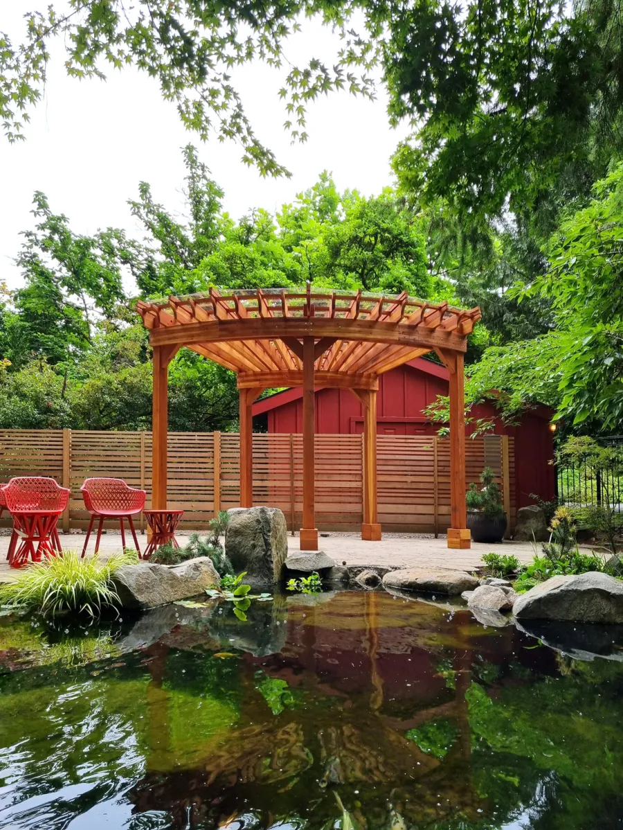 Fan Shaped Pergola Kit (Options: 15' x 18', California Redwood, Open Roof Slats at 12in, With Transparent Rain Guard, Electrical Wiring Trim Kit for 1 Post, Post Anchor Kit for Concrete, No Ceiling Fan Base, 10' Posts, No Curtain Rods, Transparent Premium Sealant). Photo Courtesy of G. Fish of Vancouver, WA.