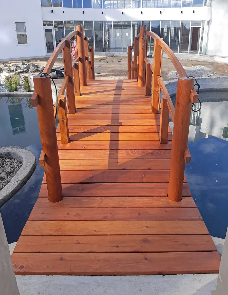 Custom Forever Foot Bridge (Options: 21' L, Mature Redwood, 5' Wide Instead of the Standard 4' Width, Arched 2x4 Handrail and Circular 6x6 Posts on Corners and Center by Custom Request, Transparent Premium Sealant). Photo Courtesy of Hino Medical Center of Ensenada, Baja California, Mexico.