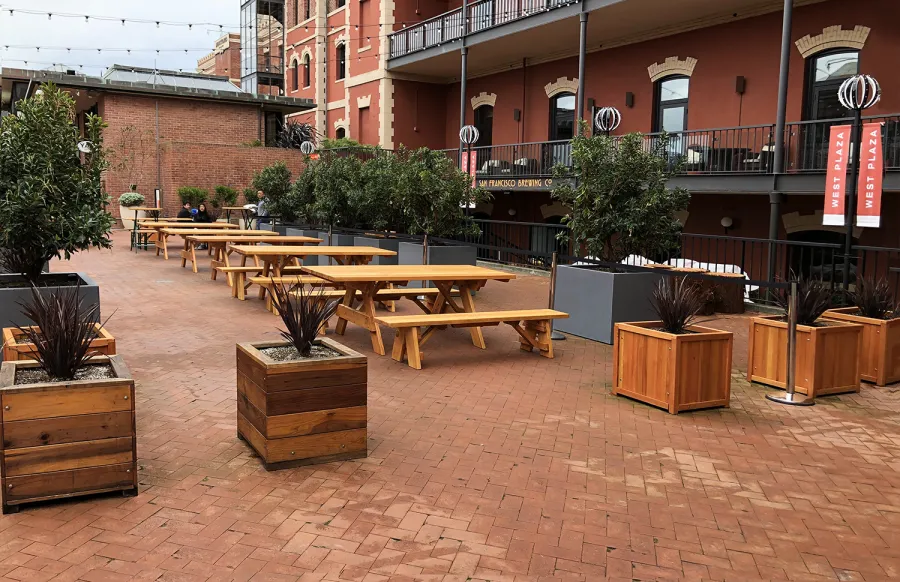 Forever Picnic Tables (Unattached Benches) (Options: 7' L, 34 ½in W, Some Table with No Seating and Some with Side Benches, Douglas-fir,1 Full Length Side Bench Per Side, Standard Tabletop, Slightly Rounded Corners, No Umbrella Hole, Transparent Premium Sealant). Photo also shows some Mendocino and Napa Planters. Photo Courtesy of A. Frost. Installed at Ghirardelli Square, West Plaza Beer Garden, located at 900 North Point Street at the corner of Beach & Larkin Streets, San Francisco, CA.