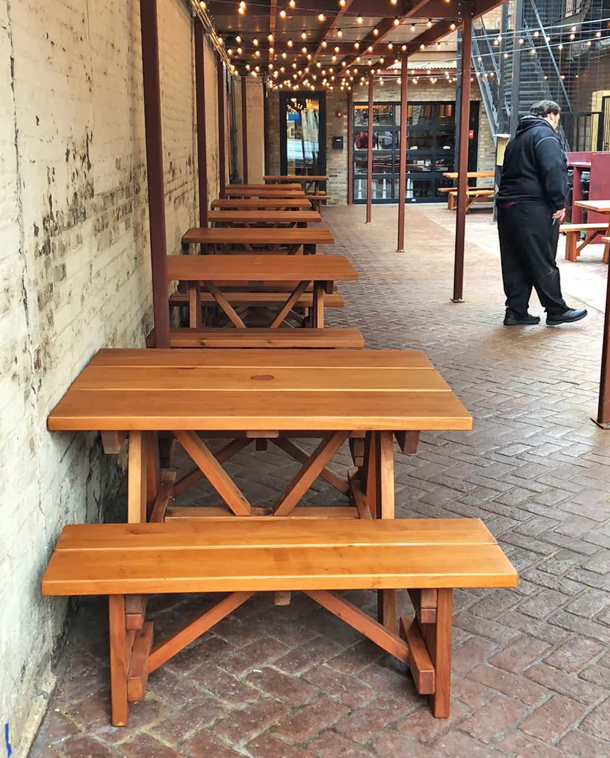 Forever Picnic Tables (Unattached Benches) (Options: 4', 34 ½in W, Side Benches, Mature Redwood, 1 Full Length Side Bench Per Side, Standard Tabletop, Squared Corners, 2in Umbrella Hole, Transparent Premium Sealant). Standard design is with 5 3/4" wide boards. The tabletops in this photo were built for the restaurant by request using bookend construction (where 2 standard width 5 3/4" wide boards are tongue and grooved together to appear as one wider 11 1/2" wide board). If you would like this effect for your tables, just add a note saying want bookend detail added to your order (no extra charge to do this). Photo courtesy of M. Piekarz of Chicago, IL.