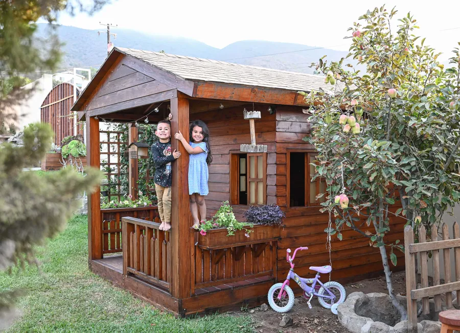 Kid's Backyard Cabin (Options: 12ft L x 8ft W, 7ft Wall H, Douglas-Fir, 4ft Front Porch Size [Included in the Overall Length], Interior Decking, Transparent Premium Sealant). Photo shows structure recently resealed after 6 years of loving service.