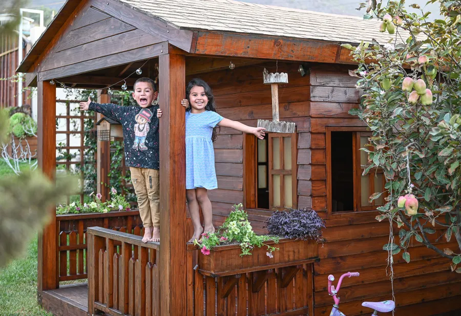 Kid's Backyard Cabin (Options: 12ft L x 8ft W, 7ft Wall H, Douglas-Fir, 4ft Front Porch Size [Included in the Overall Length], Interior Decking, Transparent Premium Sealant). Photo shows structure recently resealed after 6 years of loving service.