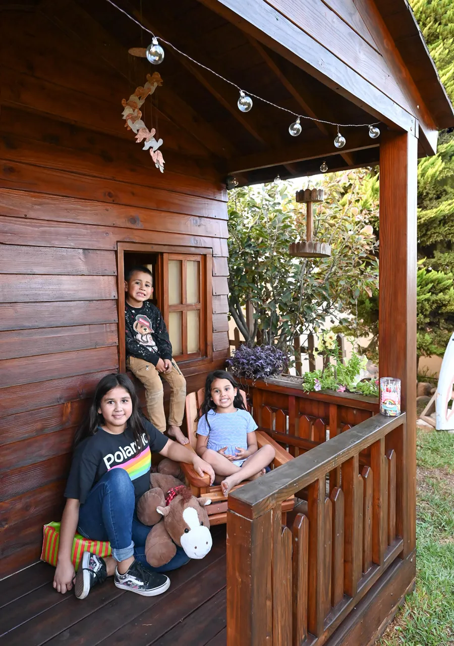 Kid's The Backyard Cabin (Options: 12ft L x 8ft W, 7ft Wall H, Douglas-Fir, 4ft Front Porch Size [Included in the Overall Length], Interior Decking, Transparent Premium Sealant). Photo shows structure recently resealed after 6 years of loving service.