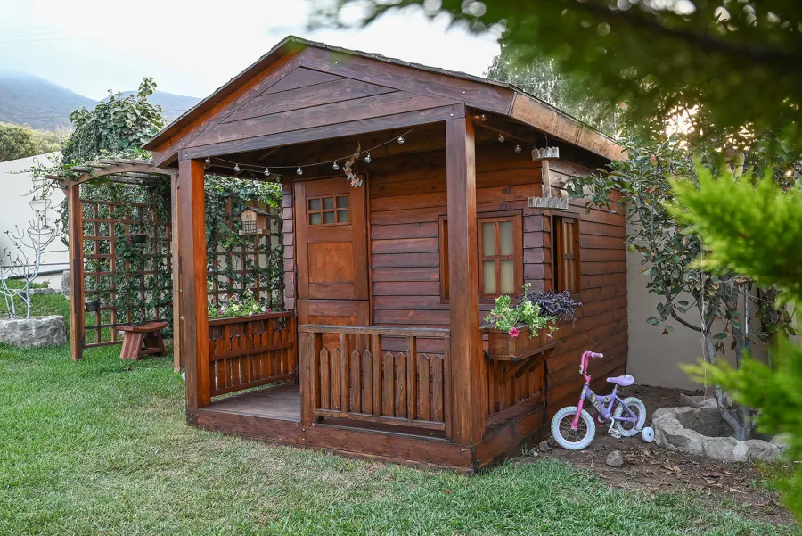 Kid's Backyard Cabin (Options: 12ft L x 8ft W, 7ft Wall H, Douglas-Fir, 4ft Front Porch Size [Included in the Overall Length], Interior Decking, Transparent Premium Sealant). Photo shows structure recently resealed after 6 years of loving service.