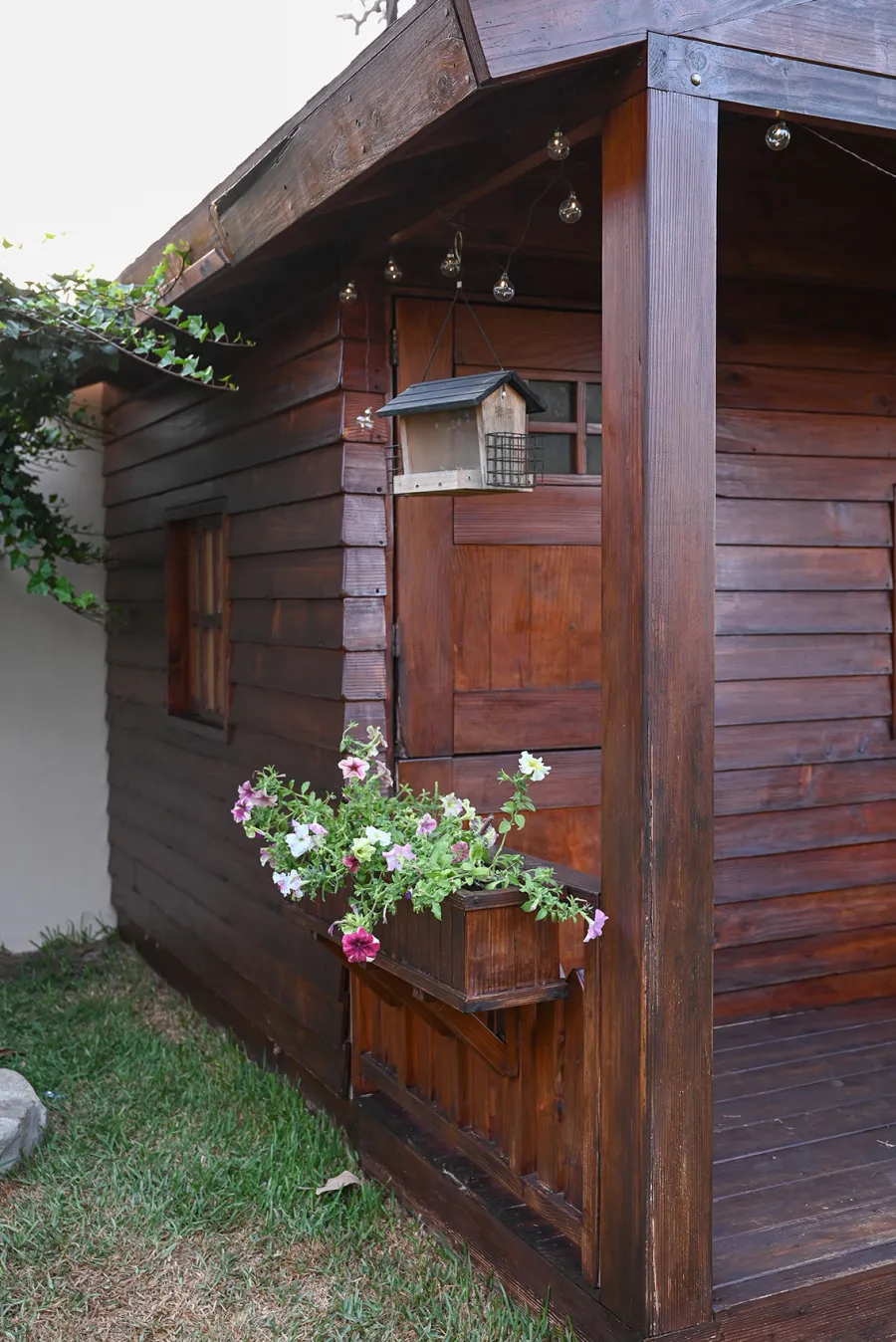 Kid's Backyard Cabin (Options: 12ft L x 8ft W, 7ft Wall H, Douglas-Fir, 4ft Front Porch Size [Included in the Overall Length], Interior Decking, Transparent Premium Sealant). Photo shows structure recently resealed after 6 years of loving service.