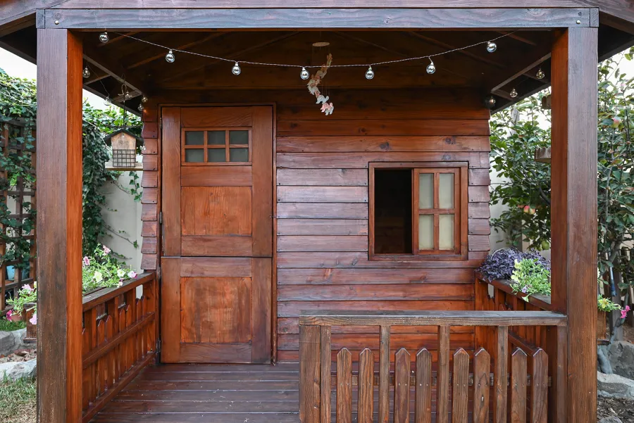 Kid's Backyard Cabin (Options: 12ft L x 8ft W, 7ft Wall H, Douglas-Fir, 4ft Front Porch Size [Included in the Overall Length], Interior Decking, Transparent Premium Sealant). Photo shows structure recently resealed after 6 years of loving service.