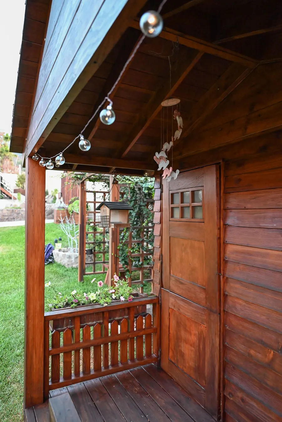 Kid's Backyard Cabin (Options: 12ft L x 8ft W, 7ft Wall H, Douglas-Fir, 4ft Front Porch Size [Included in the Overall Length], Interior Decking, Transparent Premium Sealant). Photo shows structure recently resealed after 6 years of loving service.