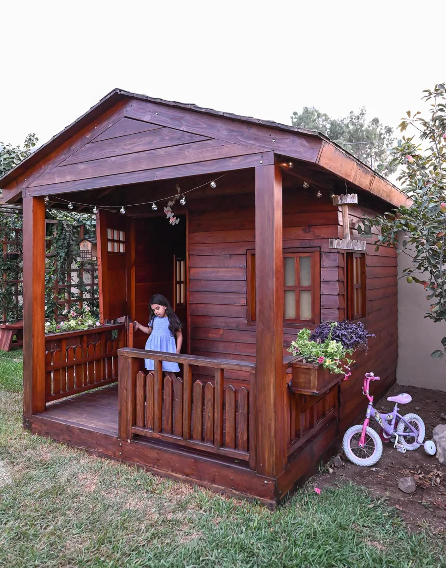Kid's Backyard Cabin (Options: 12ft L x 8ft W, 7ft Wall H, Douglas-Fir, 4ft Front Porch Size [Included in the Overall Length], Interior Decking, Transparent Premium Sealant). Photo shows structure recently resealed after 6 years of loving service.