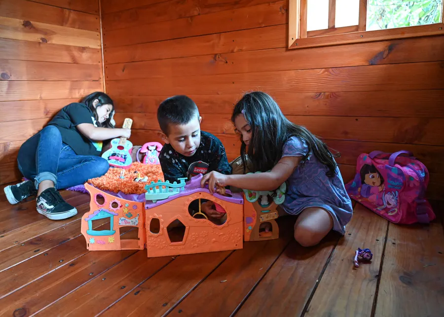 Kid's The Backyard Cabin (Options: 12ft L x 8ft W, 7ft Wall H, Douglas-Fir, 4ft Front Porch Size [Included in the Overall Length], Interior Decking, Transparent Premium Sealant). Photo shows structure recently resealed after 6 years of loving service.