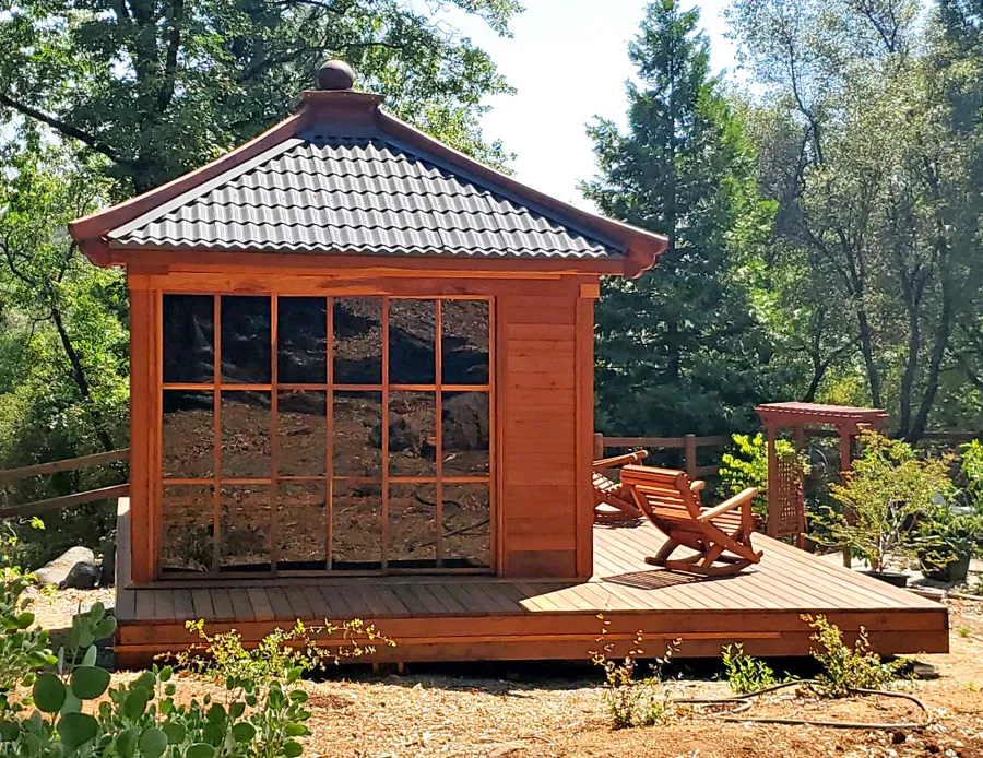 Custom Kikue's Tea House (Options: 14' x 12', 8' Wall Height, Metal Roof [Slate Gray, Metal Tile - Stile Style by bestbuymetals.com], California Redwood, with Solid Walls by Custom Request, Interior and External Decking, 6' Deck on the Front Side and 3' Decks on the Sides, Transparent Premium Sealant). Photo Also Shows 2 Ensenada Rocking Chairs. Photo Courtesy of A. Hagadron of Rough Ready, CA.