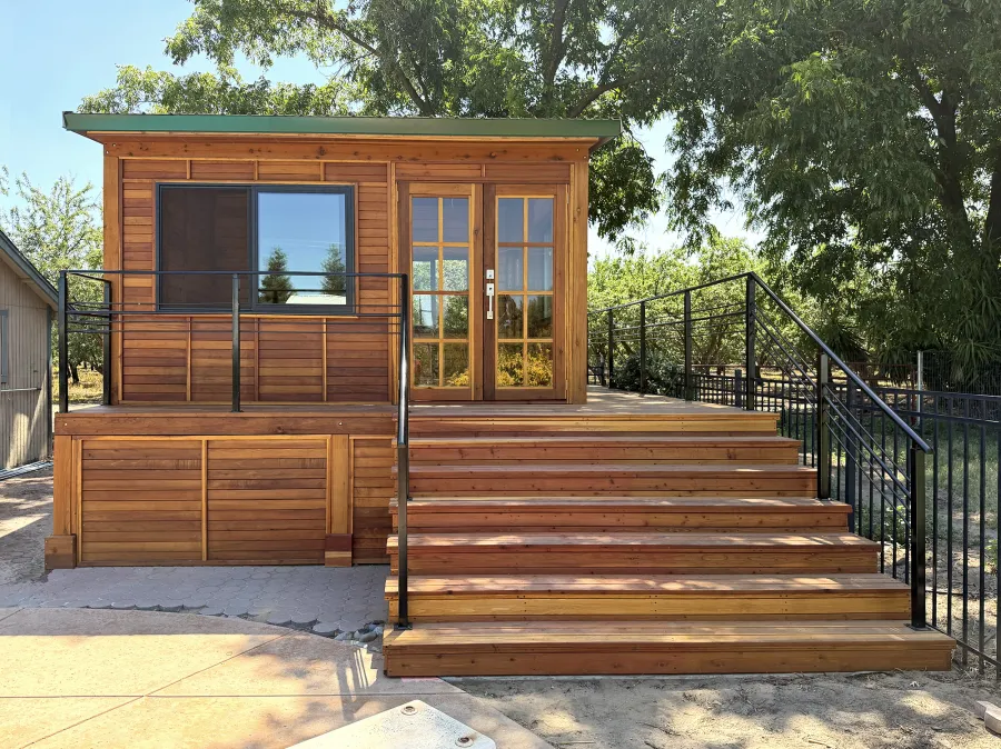 Custom Palo Alto Backyard Cabin (Options: 18' L, 16' W, With 19' x 19' Structural Deck with Steps, California Redwood for Exterior Finished, Douglas-fir Internal Walls and Framing, Double Door, Slidding Windows, Windows Purchased Locally, With Two 2' x 2' Skylights, Metal Roof, Electrical Wire Trim on the Walls, Transparent Premium Sealant). Photo Courtesy of R. and M. Hegwood of Ceres, CA.