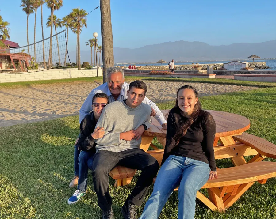 Round Wooden Picnic Table (Attached Benches) (Options: 5' Diameter, Attached Benches, Mosaic Douglas-Fir, Standard Tabletop, No Lazy Susan, 2" Umbrella Hole, Transparent Premium Sealant). Photo courtesy of El Estero Beach Resort in Ensenada, Mexico.