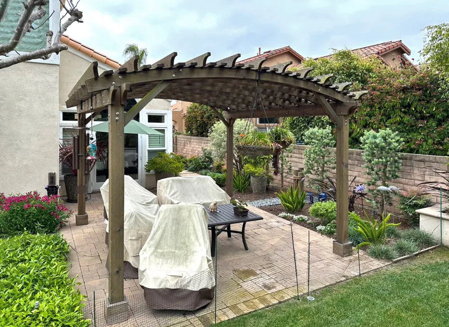 Sebastopol Pergola (Options: 14' L x 14' Arc W, Mature Redwood, 2 Electrical Wiring Trims, 4-Post Anchor Kit for Concrete, No Ceiling Fan Base, 9' Post Height, Transparent Premium Sealant). The photo shows a Pergola that is 10 years old and has no maintenance. The photo is Courtesy of J. Cheetham of Laguna Niguel, CA.