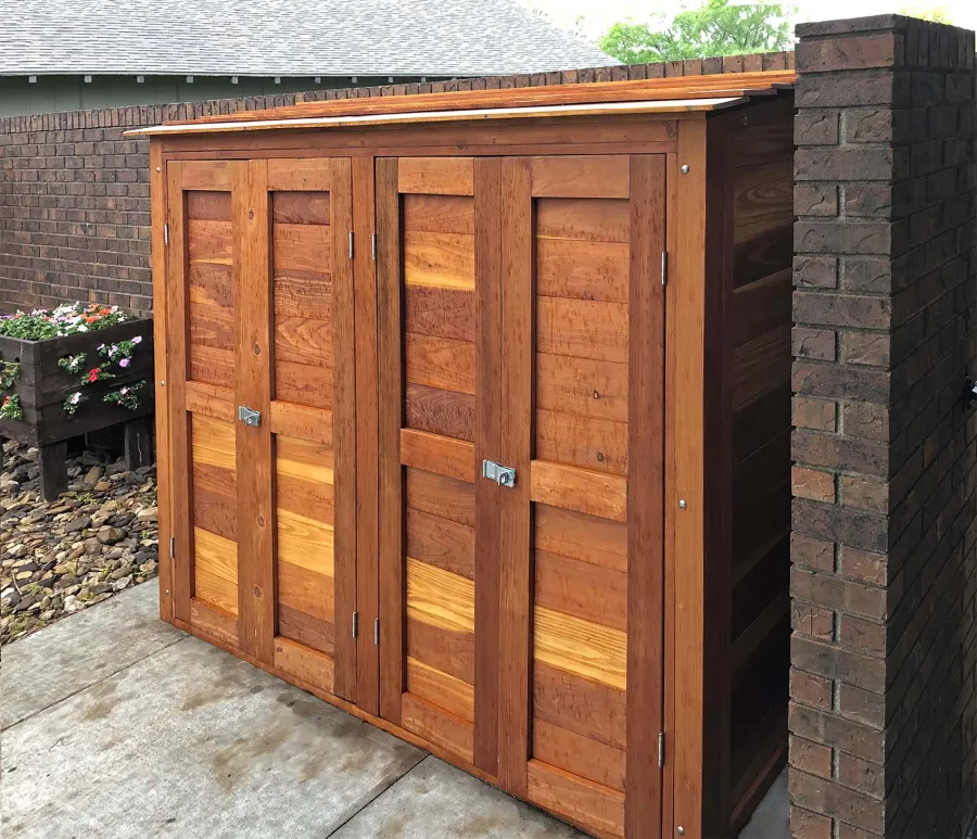 Storage Shed (Options: 8' W, 2' D, 5' H, California Redwood, Double Doors Opening Out From Center, Three Shelves at 18" H, 36" H and 50" H, Hardware Kit for Wood, Transparent Premium Sealant). Photo Taken When Rain Started. Photo Courtesy of J. Foster of Great Bend, Kansas.