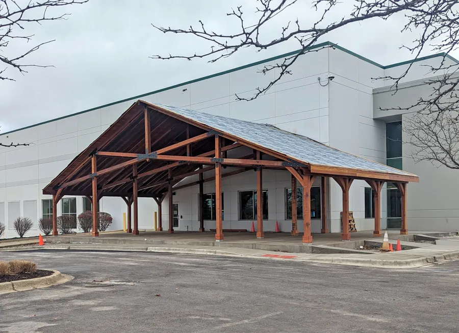 Esther Scissor Truss Pavilion (Options: 33’ L x 63’ W, California Redwood, Standard 3/4" T&G Roof Boards, 16' and 10' H Posts by Custom Request, with 4 Ceiling Fan Bases, High-Wind Post Anchors, 5:12 Roof Pitch, Transparent Premium Sealant). Installation in Process, Photo Shows the Final Roofing Only Partially Installed. Photo Courtesy of the HelloFresh Produce Company of Bolingbrook, IL.