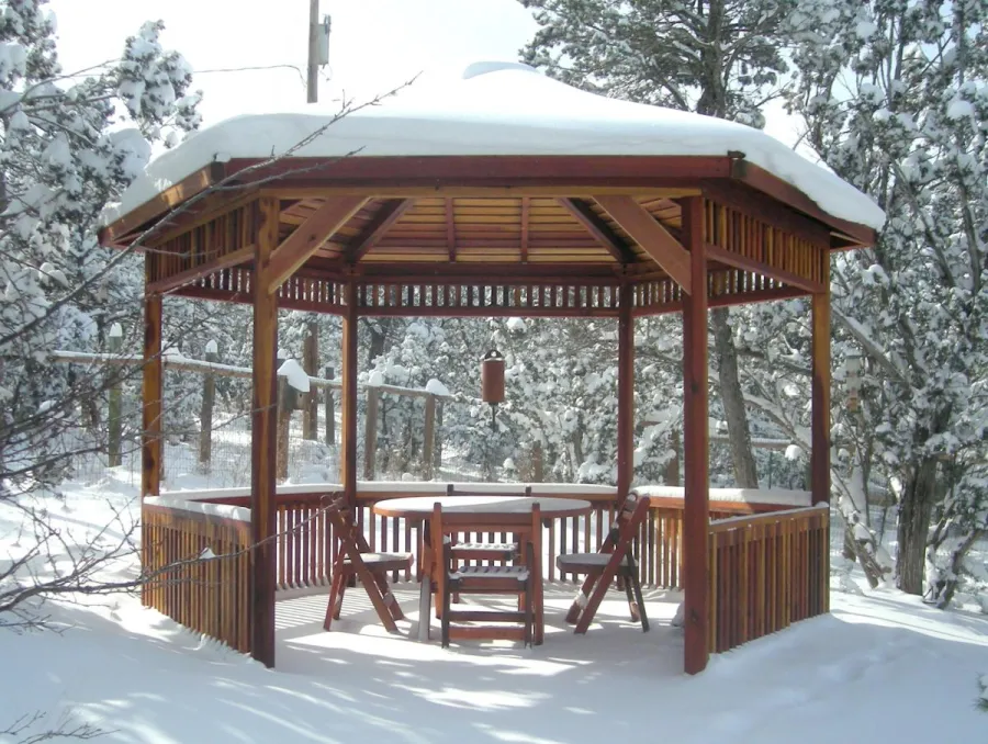 Hexagonal Retreat Pavilion (Options: 14' Diameter, No Deck, California Redwood, With Upper and Lower Panels, Transparent Premium Sealant).  Round Folding Table Set with Chairs Under Pavilion. Photo Courtesy of Ms. Karen McCartney of Tijeras, NM.  