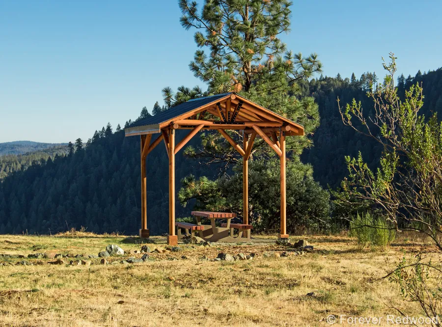 Humboldt Log Pavilion (Options: 6in x 6in Posts Thickness, 12ft L x 12ft W, No Privacy Panels, California Redwood, 2 Fascia Boards for Gutters, 9.5ft Post Height, No Electrical Wiring Trim, 4-Post Anchor Kit for High-Wind, No Ceiling Fan Fan Bases, No Curtain Rods, Transparent Premium Sealant). Metal Roof Installed by Custom Request.