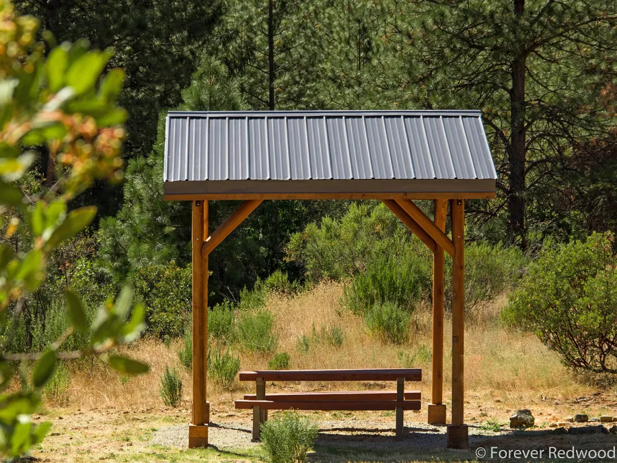 Humboldt Log Pavilion (Options: 6in x 6in Posts Thickness, 12ft L x 12ft W, No Privacy Panels, California Redwood, 2 Fascia Boards for Gutters, 9.5ft Post Height, No Electrical Wiring Trim, 4-Post Anchor Kit for High-Wind, No Ceiling Fan Fan Bases, No Curtain Rods, Transparent Premium Sealant). Metal Roof Installed by Custom Request.