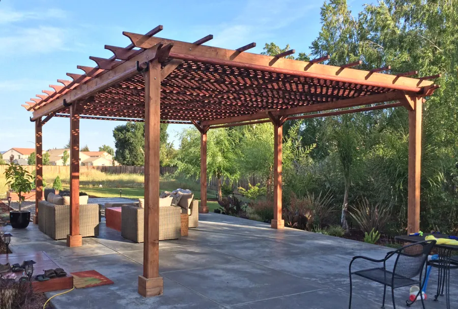 Lattice Pergola Kit (Options: 25' L x 18' W, California Redwood, No Electrical Wiring Trim, Lengthwise Roof Support Timbers, 6-Post Anchor Kit for Concrete, No ceiling Fan Base, No Privacy Panels, 4 Curtains Rods, 9.5' Post Height, Transparent Premium Sealant). 2x2 Slats Above Rafters was Added as Custom Detail. It is not Part of Standard Design. Photo Courtesy of Tom Deckowski of Morgan Hill, CA. Note that photo shows 2 yr old finish that is partially faded.