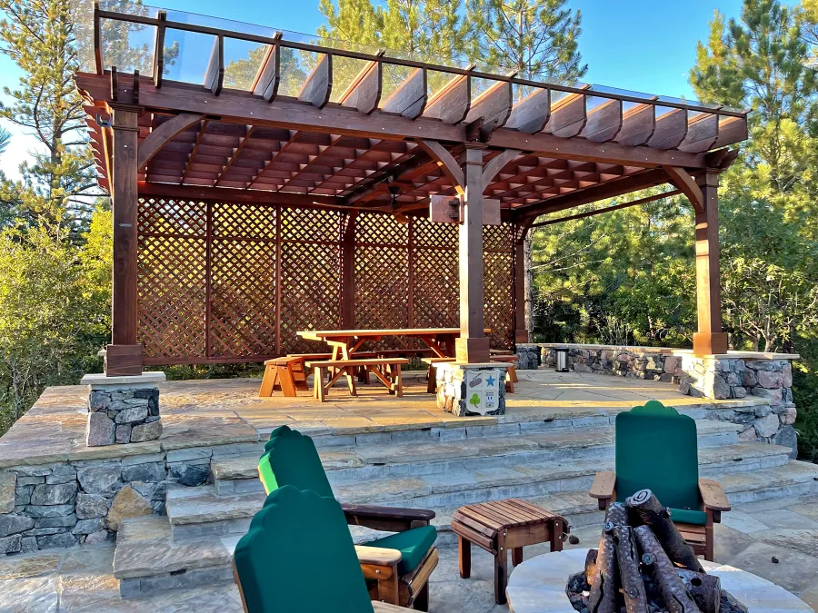 Montvale Pergolas (Options: 24' x 16', Mature Redwood, 6-Post Anchor Kit for Concrete, 1 Ceiling Fan Base and 1 T.V. Base, 2 Curtain Rods, 1 Lattice Privacy Panel, 9.5' H Posts, with Rain Guard, Coffee-Stain Premium Sealant). Photo Also Shows Some Adirondack Chairs with Ottoman. Photo Taken 1 Year After Installation, and After Restaining. Photo Courtesy of J. Brinkman of Castle Rock, Colorado.