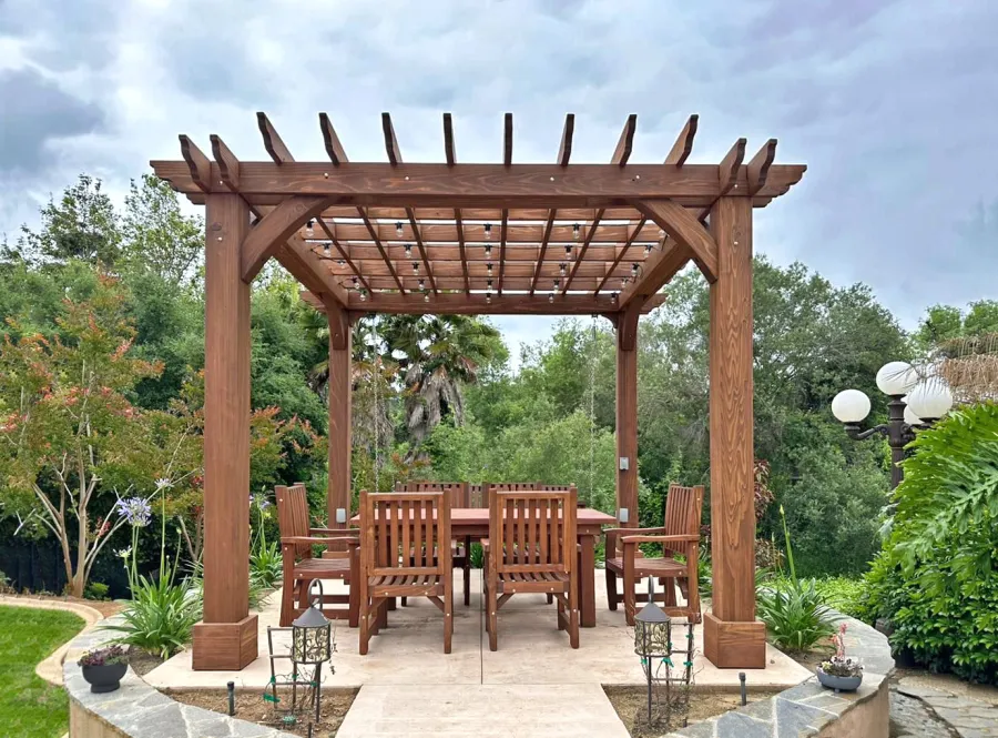 Montvale Pergola (Options: 12' x 12', California Redwood, 4-Post Anchor Kit for Concrete, No Ceiling Fan Base, No Curtain Rods, No Privacy Panels, 9.5' H Posts, Coffee-Stain Premium Sealant). Photo Also Shows a San Francisco Patio Table Set with Ruth Chairs. Photo Courtesy of M. Dopudja of Fallbrook, CA.