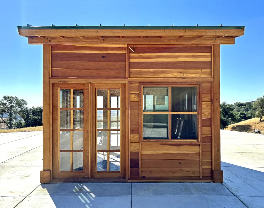 Palo Alto Backyard Cabin (Options: 10' L, 12' W, Without Porch, California Redwood for Exterior Finished, Douglas-fir Internal Walls and Framing, With 2 French Doors, Slidding Windows, Windows Purchased Locally, With 4' x 4' Skylight, Metal Roof, Electrical Wire Trim on the Walls, Transparent Premium Sealant). Photo Courtesy of M. Diaz of Fairfield, CA.