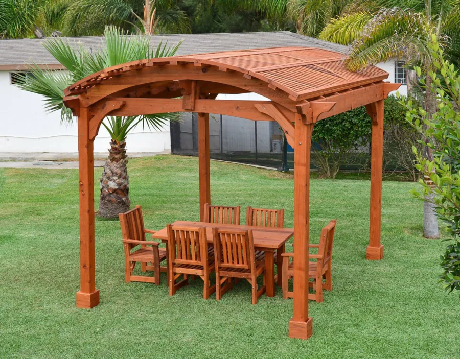 Viking Pergola DIY Kits (Options: 12' L x 14' W, Mature Redwood, No Electrical Wiring Trim Kit, No Curtain Rods, Transparent Premium Sealant). Photo Also Shows a Patio Table Set with Ruth Chairs Under the Pergola. 
