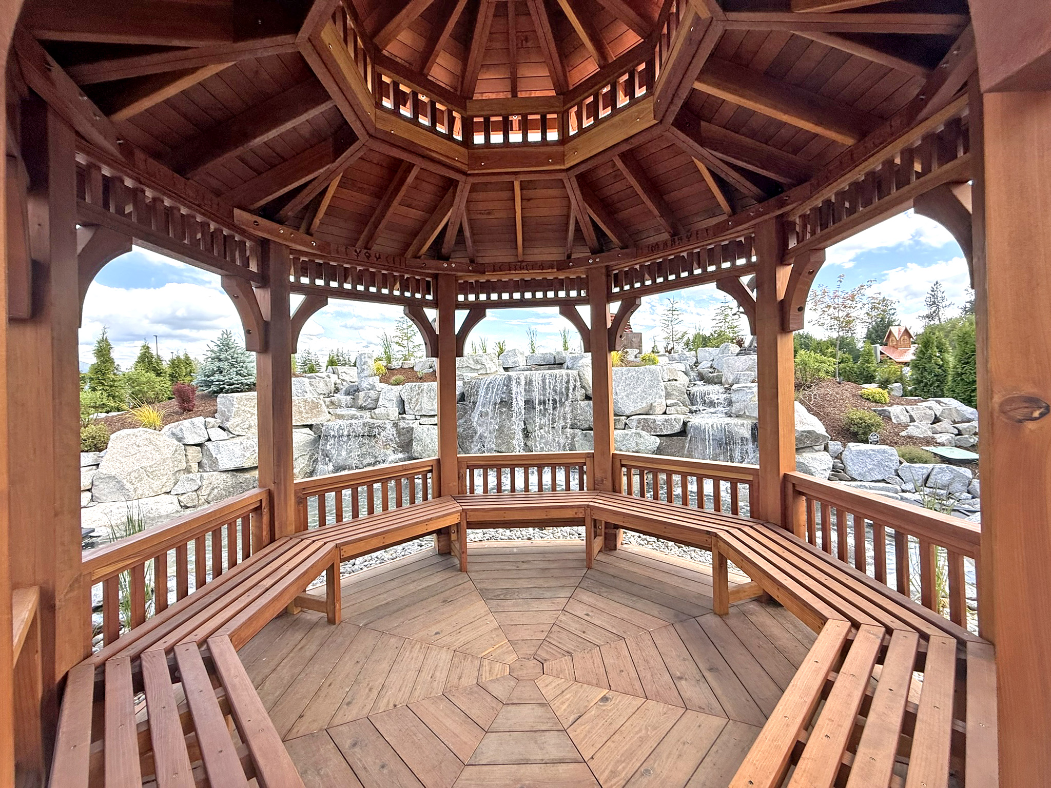 Custom Octagonal Pavilion (Options: 14' Diameter, Mature Redwood, 8' H Posts, 6x6 Posts, with Seating Area Under the Pavilion, Post Anchor Kit for High-Wind, Transparent Premium Sealant). Installed in Faith Walk Community Fitness Park in Coeur d'Alene, Idaho.