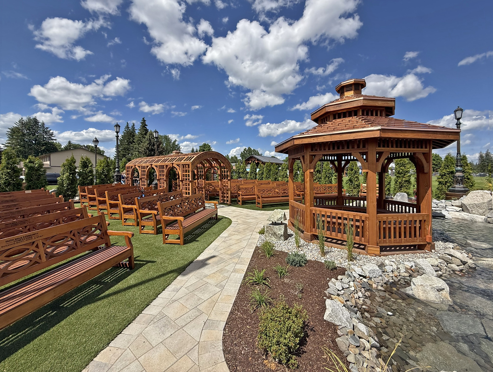 Custom Octagonal Pavilion (Options: 14' Diameter, Mature Redwood, 8' H Posts, 6x6 Posts, with Seating Area Under the Pavilion, Post Anchor Kit for High-Wind, Transparent Premium Sealant). Photo Also Shows a Victorian Trellis and Some Hennell Benches. Installed in Faith Walk Community Fitness Park in Coeur d'Alene, Idaho.