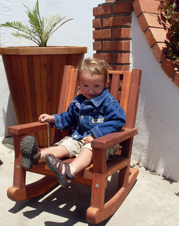 Little Raulito enjoying a Forever Redwood Kids Rocking Chair. Behind him stands a Vase Planter. Proceeds from the sale of Forever Redwood go toward Redwood forest restoration work.